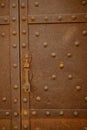 Iron door with studs and lock. Rusted iron sheet of an ancient door. It has mullioned windows with marble columns Royalty Free Stock Photo