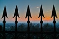 Old iron fence arrowhead tips against dusky sky with misty horizon
