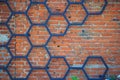 Iron forged decorative pattern of black metal in the shape of a honeycomb on the background of a red brick wall Royalty Free Stock Photo