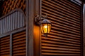 Iron forged retro lantern with a glass shade and an electric light bulb. Royalty Free Stock Photo