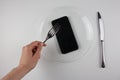 An iron fork and knife with a phone on a transparent dish.