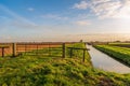 Iron gate between two wooden beams in the foreground of a long polder path Royalty Free Stock Photo