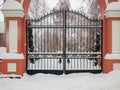 Iron gates and concrete fence at the entrance to the city Park. Winter day. The drifts of snow Royalty Free Stock Photo