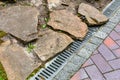 Iron grating of the drainage system near pedestrian sidewalk made of stone brick tiles. Royalty Free Stock Photo