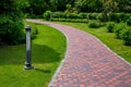Iron ground lantern garden lighting of park curved path paved with stone tiles in park. Royalty Free Stock Photo
