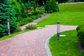 Iron ground lantern and poli garden lighting of park curved path paved with stone tiles. Royalty Free Stock Photo