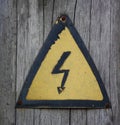 Iron high voltage sign. Nailed to a wooden post. Yellow. Closeup