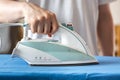 Iron on an ironing board with a blue shirt close up from the sid Royalty Free Stock Photo