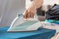 Iron on an ironing board with a blue shirt close up from the sid Royalty Free Stock Photo