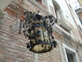 Iron lamp. Vintage forged Venetian street lantern. Delicate metal decorations. In the background a brick wall of a house