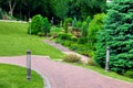 Iron lantern ground and pillar garden lighting of park curved path paved with stone tiles. Royalty Free Stock Photo