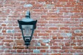 An iron lantern hangs on an old brick wall. in the lamp modern lamp is twisted. texture Royalty Free Stock Photo