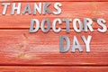 Iron letters thanks doctors day lying on a wooden textured boards