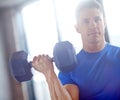 Iron man in the making. Portrait of a handsome young man lifting a dumbell in a gym.