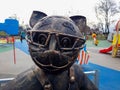 Iron metal figurine of a statue of a cat with glasses in a city children's park Royalty Free Stock Photo