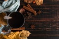 Iron mug with black coffee, spices, on a background of a scarf, dry leaves on a wooden table. Autumn mood, a warming drink. Copy