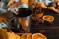 Iron mug with black coffee, spices, dry oranges, on a background of a scarf, dry leaves on a wooden table. Autumn mood, a warming Royalty Free Stock Photo