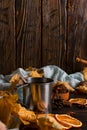 Iron mug with black coffee, spices, dry oranges, on a background of a scarf, dry leaves on a wooden table. Autumn mood, a warming Royalty Free Stock Photo