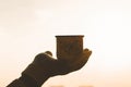 Iron mug with hot tea in female hands in knitted mittens in a winter frosty day on the sunset sky background