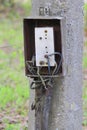 Iron old broken open distribution electric box on a concrete pole. The bare aluminum wires. Electric cables and Royalty Free Stock Photo