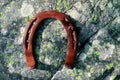 Iron old horseshoe on the mossy stone, forest. Metal rusty lucky