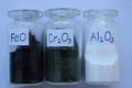 Metal oxides in three glass jars with chemical formulas.