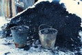 Iron pails with coal near a small pile of coal