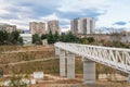 Iron pedestrian bridge over a small canyon painted in white. Tbilisi