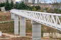 Iron pedestrian bridge over a small canyon painted in white. Tbilisi