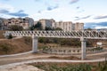 Iron pedestrian bridge over a small canyon painted in white. Tbilisi