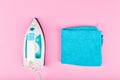 Iron on a pink background. View from above. iron with white and blue. With turquoise towel Royalty Free Stock Photo