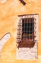 Iron rebar cage, protecting an open window and flower box, in 1500\'s building, Italy