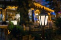 Iron retro lantern of cafe lighting glowe with warm light in the night garden.