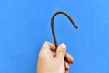Iron rusty hook in hand on a blue background Royalty Free Stock Photo