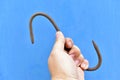 Iron rusty hook in hand on a blue background Royalty Free Stock Photo