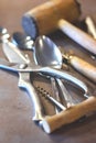 Iron spoons and other tableware lying on a concrete worktop.