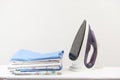 Iron and a stack of ironed clothes and baby diapers on a white background with space for text. Royalty Free Stock Photo