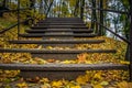 Iron staircase in the autumn forest Yellow leaves lie on the stairs. Climb on mountain \