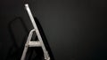 Iron step ladder against a gray wall. Preparing for home repairs. Old and dirty aluminum in an empty room, shadow. White gray Royalty Free Stock Photo