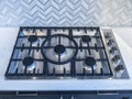 An iron stove top with stainless steel knobs inside a kitchen with a nice backsplash Royalty Free Stock Photo