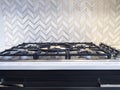 An iron stove top with stainless steel knobs inside a kitchen with a nice backsplash Royalty Free Stock Photo