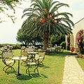 Iron tables and chairs on green lawn in the garden with flowers,