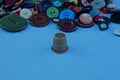 An iron thimble and a pile of colored buttons on the table