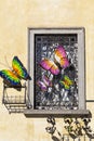 Iron window with colourful butterflies on yellow wall Royalty Free Stock Photo