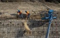 Iron workers shoveling dirt on wall of rebar and steel beams on freeway construction project Royalty Free Stock Photo