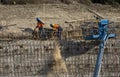 Iron workers on wall of rebar and steel beams shoveling dirt at a freeway construction project Royalty Free Stock Photo