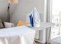 Iron for wrinkled clothes on ironing board in room Royalty Free Stock Photo