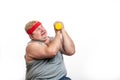 Fat funny man in red headband shows his muscles with dummbell and emotions Royalty Free Stock Photo