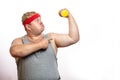 Fat funny man in red headband shows his muscles with dummbell and emotions Royalty Free Stock Photo