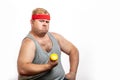 Fat funny man in red headband shows his muscles with dummbell and emotions Royalty Free Stock Photo